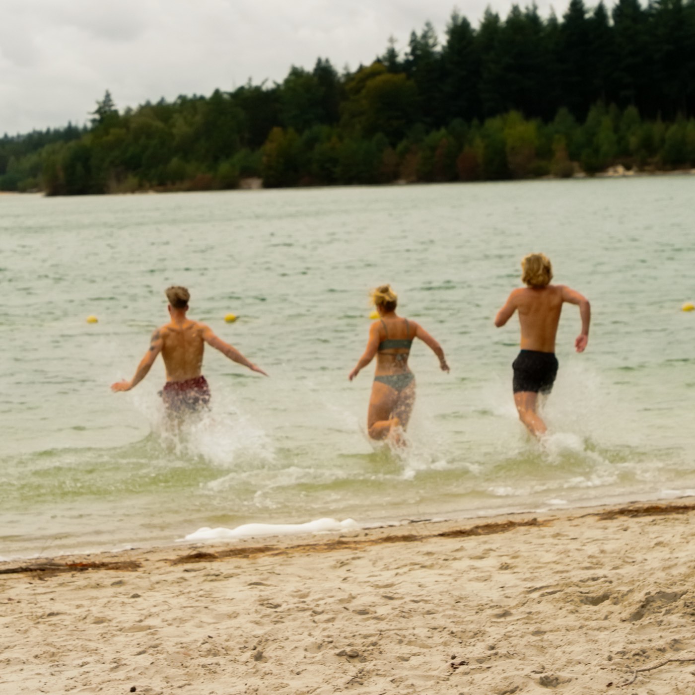 Drie vrienden rennen het meer in na de sauna